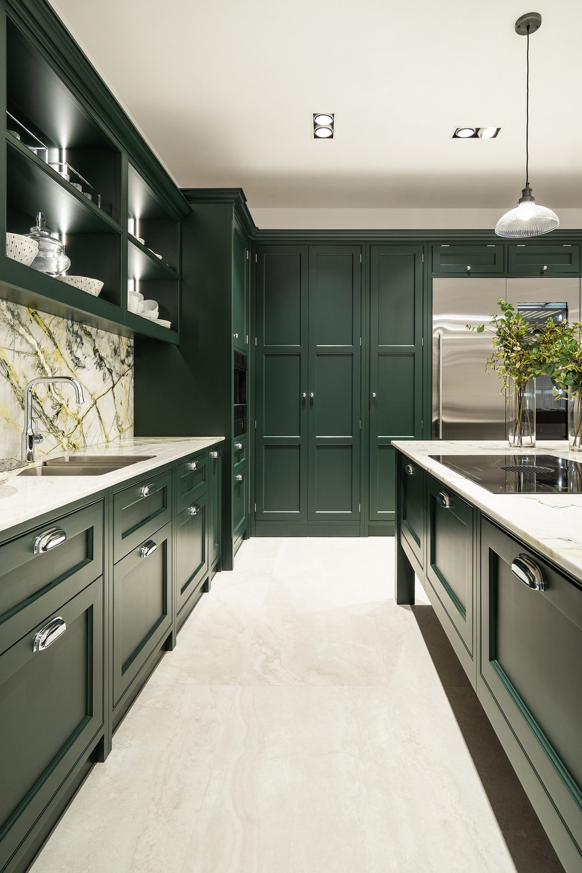 Run of green cabinetry with marble splashback and pale travertine-effect floor